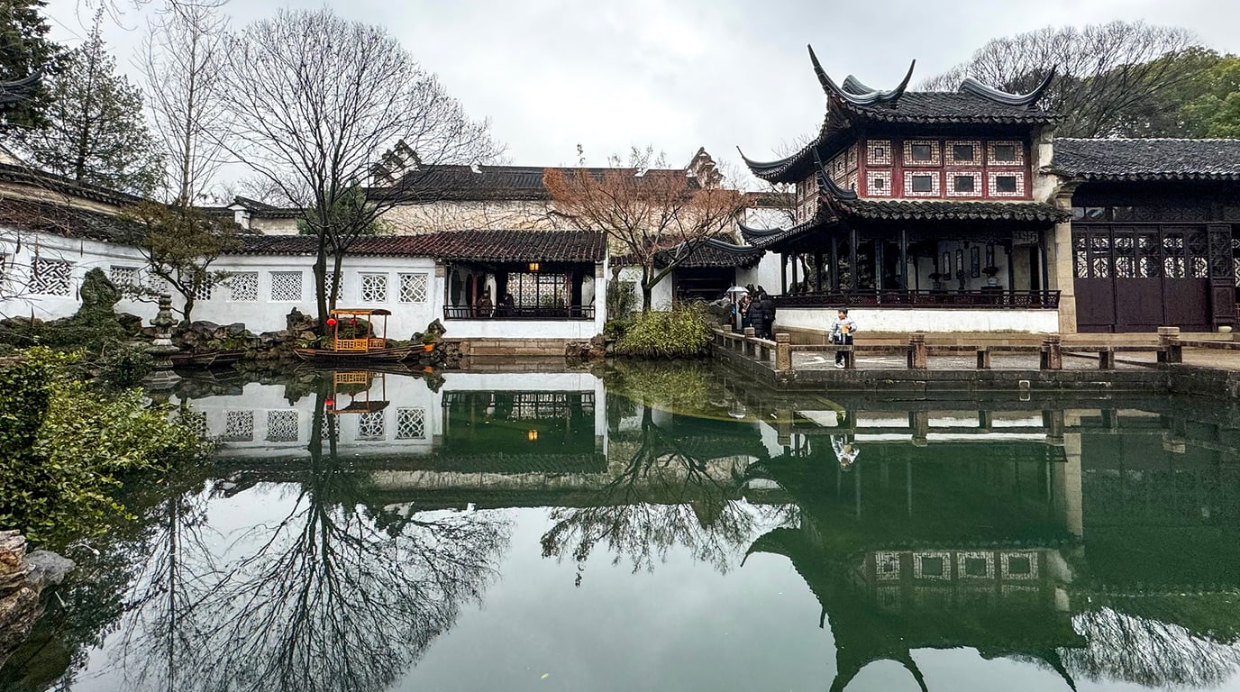 Covered walk, water, and planted rooms inside Lingering Garden in Suzhou